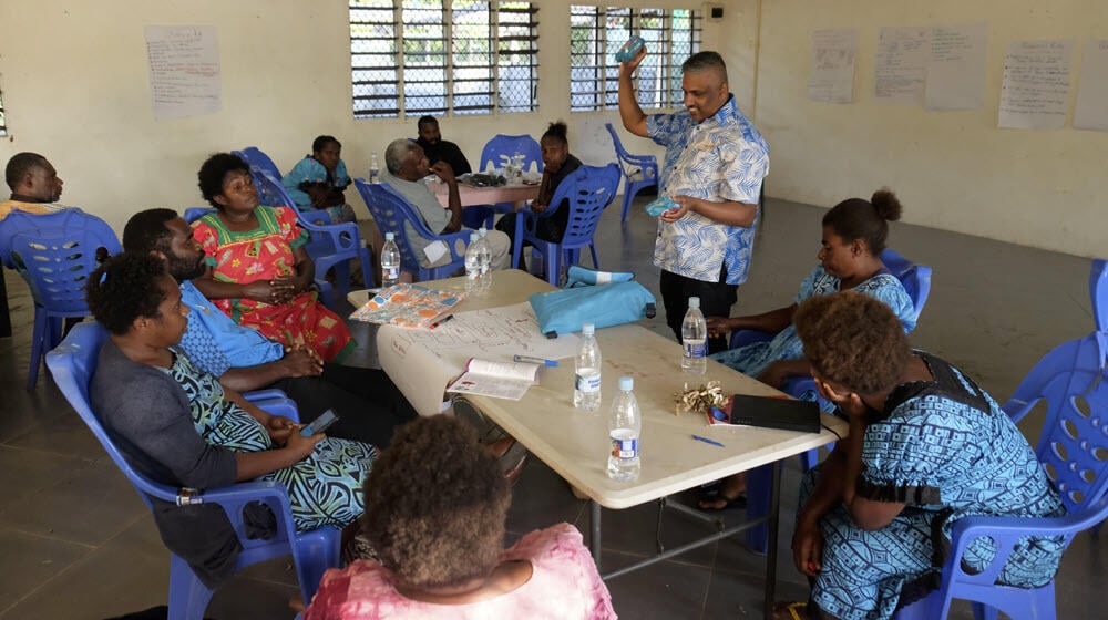 Abdul Hussain, UNFPA Pacific Specialist for Sexual and Reproductive Health in Emergencies, consulting with the cyclone-affected villagers in Tanna Island, Vanuatu, while explaining the contents of ‘UNFPA Pacific Customized Dignity Kits’  © UNFPA/David Palazón