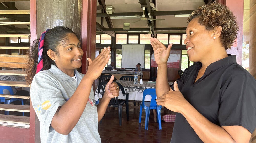 Mariana Vani interacting with her sign language interpreter at Somosomo Village Hall in Tavueni Island.