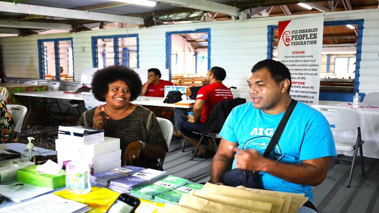 A person with disabilities engages with a health service provider with support from a sign language interpreter during the inclusive outreach session.